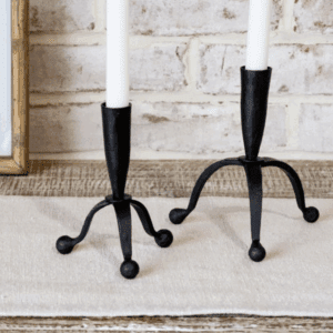 Two black candle holders with white candles on a table.